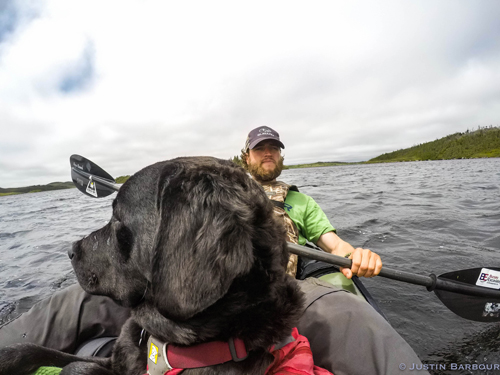 Justin Barbour exploring in his canoe with Saku looking over the horizon